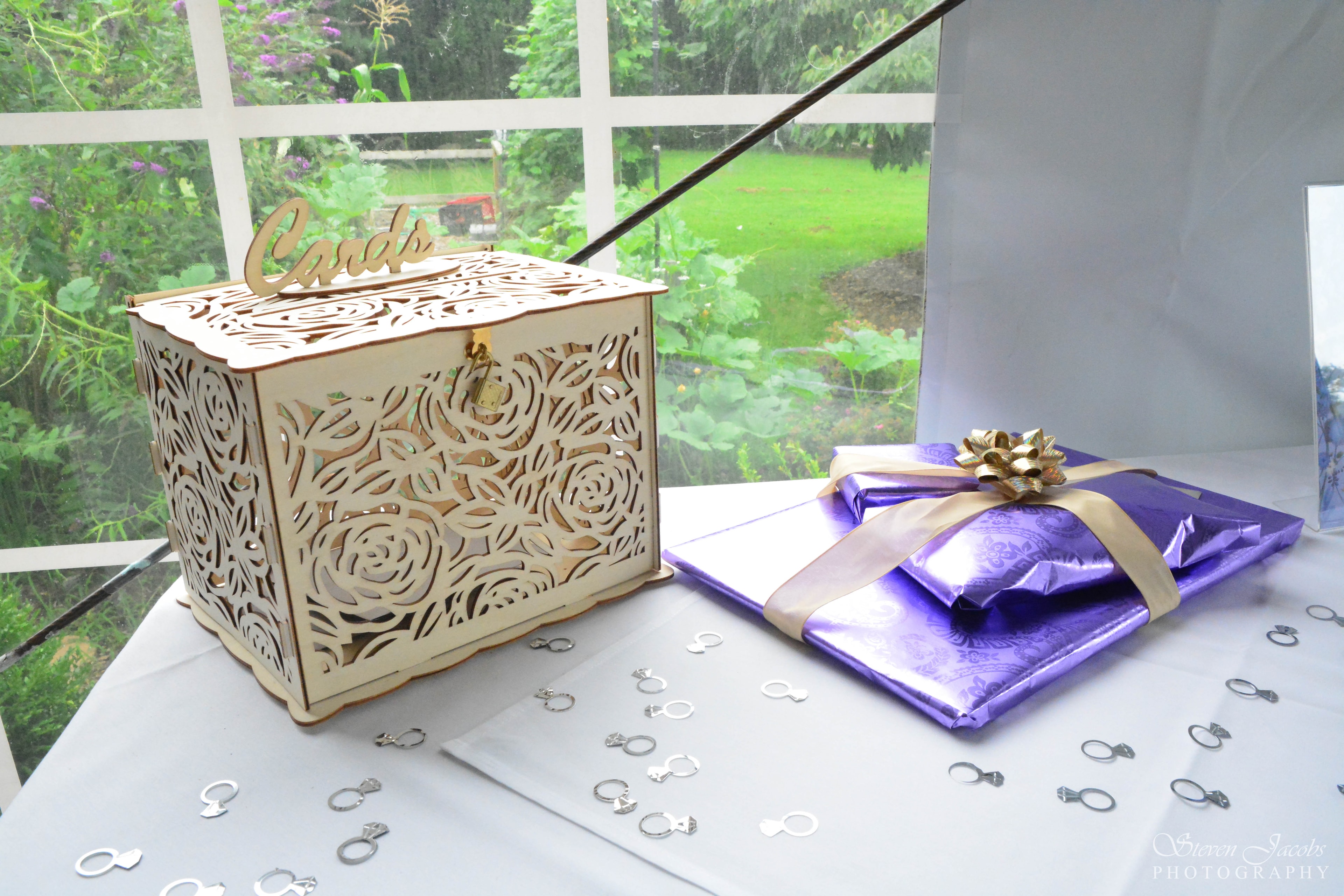 Decorative wooden card box and wrapped gift with ring confetti on a wedding table